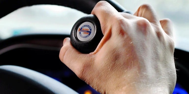 Close-up of a right hand operating a steering device attached to a steering wheel